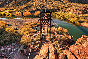 A small bridge spans a stream of water in a desert setting. By Michael Wilson