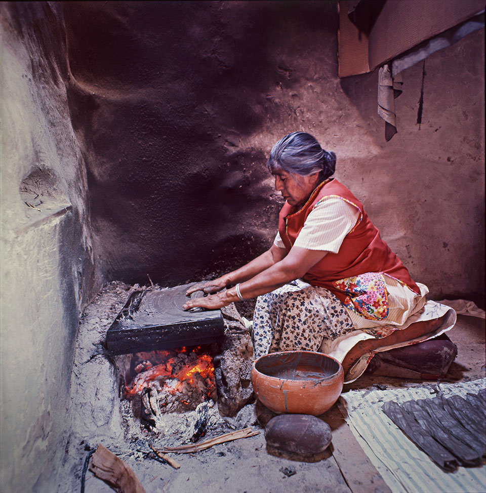 Vivian Mumzewa makes piki, a thin wafer bread made of blue corn meal and ashes, on First Mesa. The Hopi delicacy is made by spreading a thin layer of batter onto a hot stone by hand. It bakes almost instantaneously, then is rolled into a long, rather flat roll and is ready to eat.