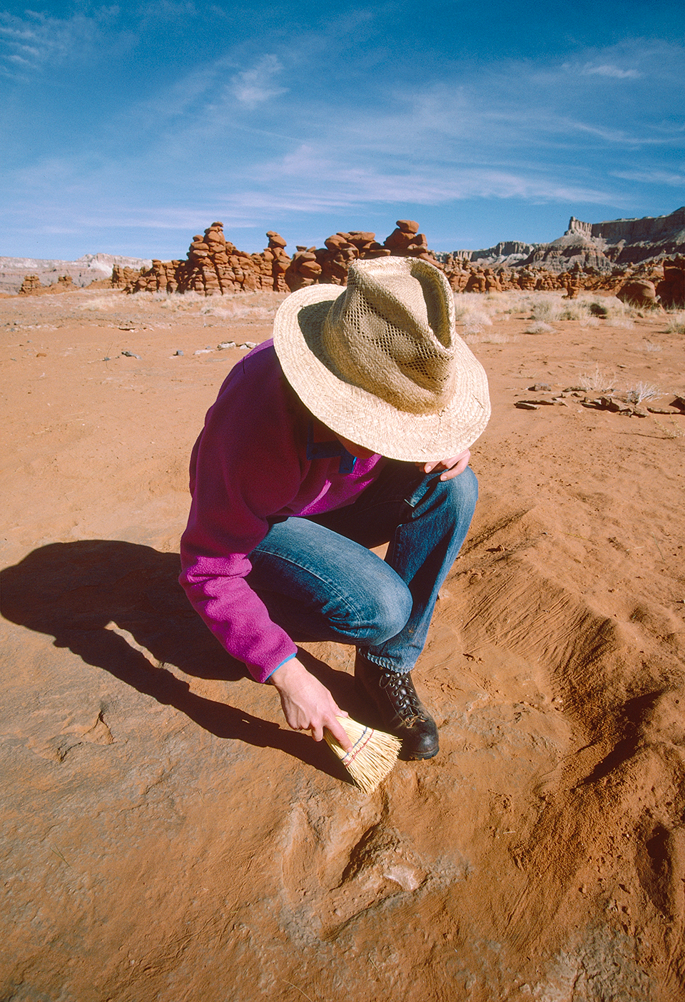 Tom Bean’s wife, Susan Lamb, removes sand from the site’s dinosaur tracks. By Tom Bean