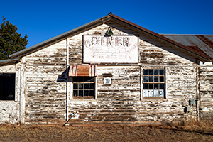 Where is this? An old wooden building with worn white paint displays a DINER sign.