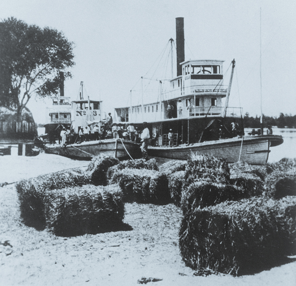 Boats including the Gila (foreground) and the Cocopah wait near hay bales at the Yuma Quartermaster Depot, a U.S. Army installation, in 1876. The depot site is now part of Colorado River State Historic Park. | THE HUNTINGTON LIBRARY