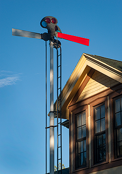 Where is this? The top of a house or building near a metal pole with ladder and two flat extensions at the top, the front of which is bright red. By Jeff Kida