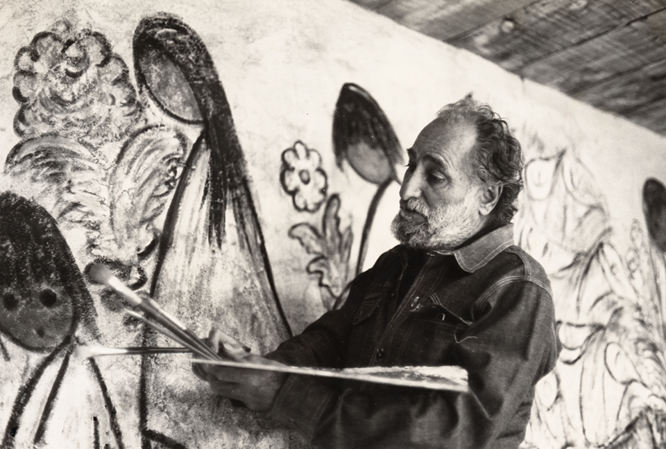 Ted DeGrazia stands with brushes and palette in front of a mural-sized painting. COURTESY OF DeGRAZIA GALLERY IN THE SUN 