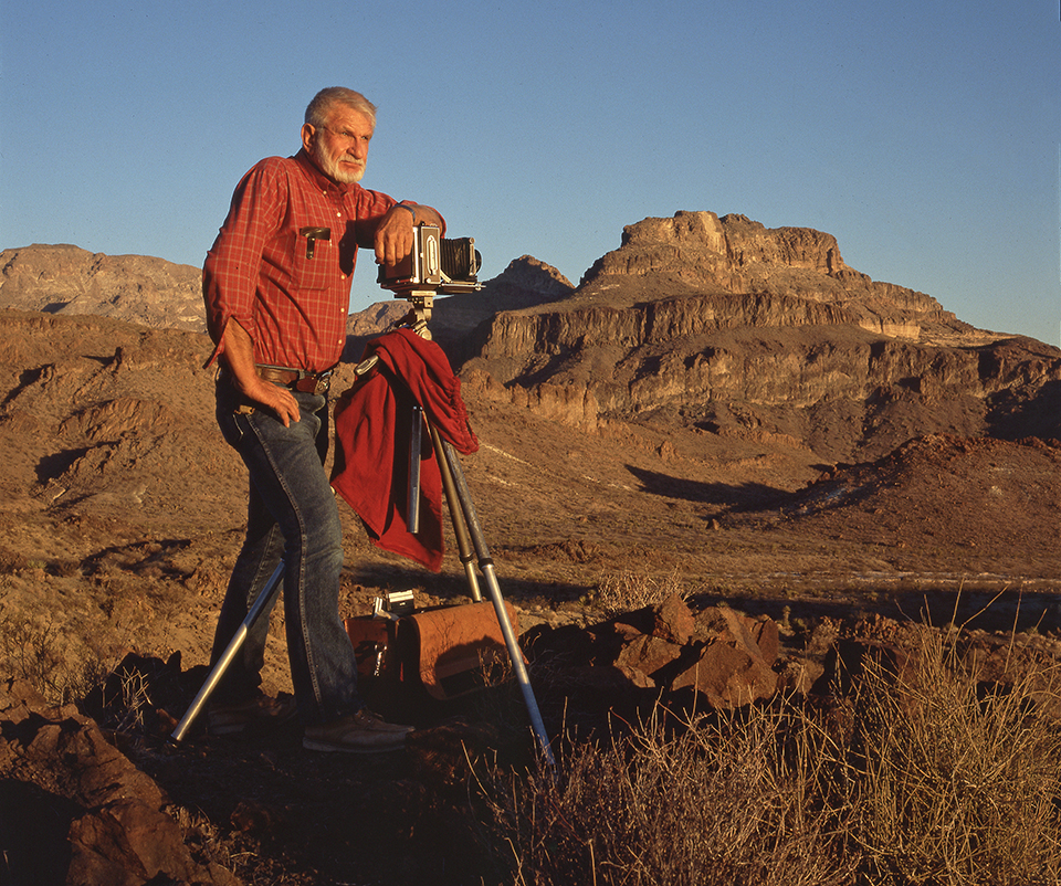 Jerry Jacka poses with a 4x5 camera mounted on a tripod in the Arizona desert. | COURTESY OF THE JACKA FAMILY