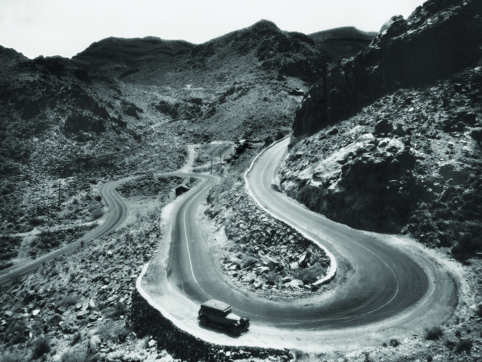 This BW photo, of a stretch of Route 66 winding through Western Arizona’s Black Mountains, is  an extreme example of challenging terrain. | Norman G. Wallace