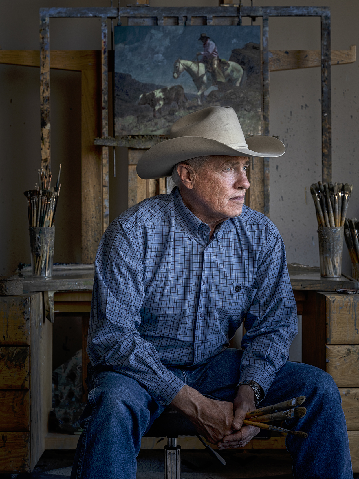 Photograph of Bill Anton holding paint brushes in his studio by Joel Grimes