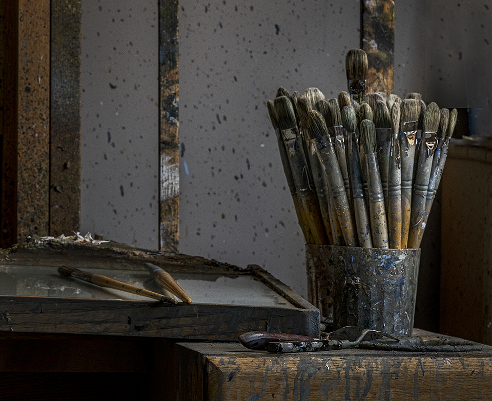 A glass filled with used paint brushes anchors a scene in Bill Anton's studio. By Joel Grimes