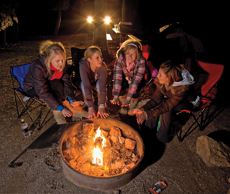 Lexi Hofmann, Misha Zelechowski, Lyndsay Martindale and Lauren Proper (left to right) warm their hands by the fire after preparing dinner over an open fire. By Peter Schwepker