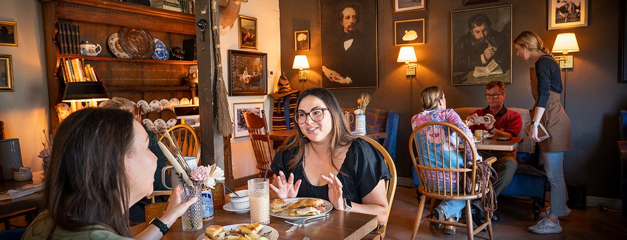 People dining at wooden tables and chairs inside the Bear & Dragon Café. By Dawn Kish
