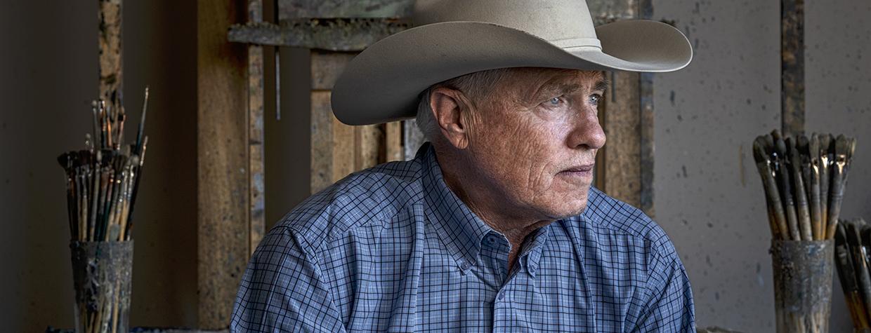 Photograph of Bill Anton holding paint brushes in his studio by Joel Grimes
