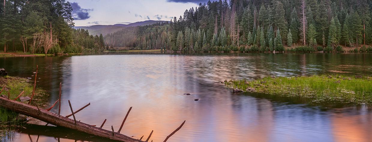 Blue sky and colorful clouds reflect off Christmas Tree Lake in Arizona's White Mountains. By Jack Dykinga
