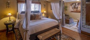 The intimate interior of a room at Kull features a poster bed, wooden floors and a separate sitting room. By John Burcham